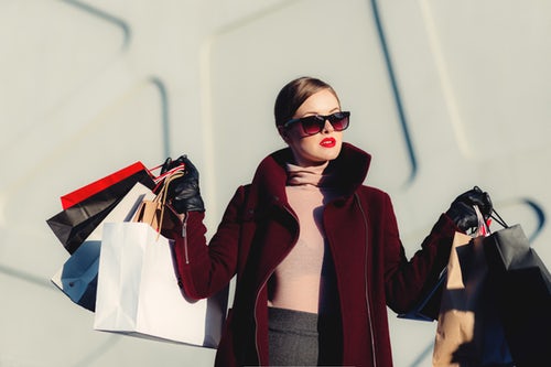 A woman holding Charlotte Russe shopping bags in front of a building.