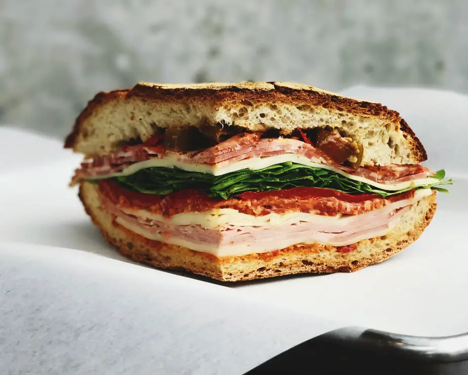A Subway sandwich with ham and spinach on a white plate.