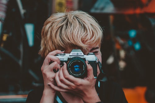 A boy is capturing a shot with an Adorama camera.