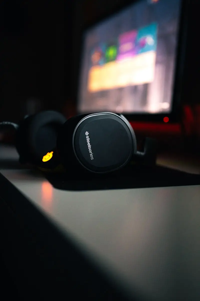 student steelseries black headphones beside turned-on flat screen monitor