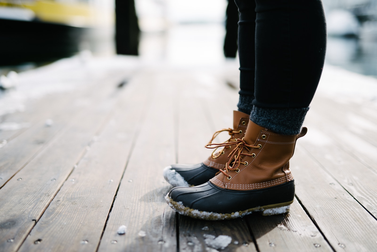 student wearing brown-and-black ll bean leather duck boots standing on dock