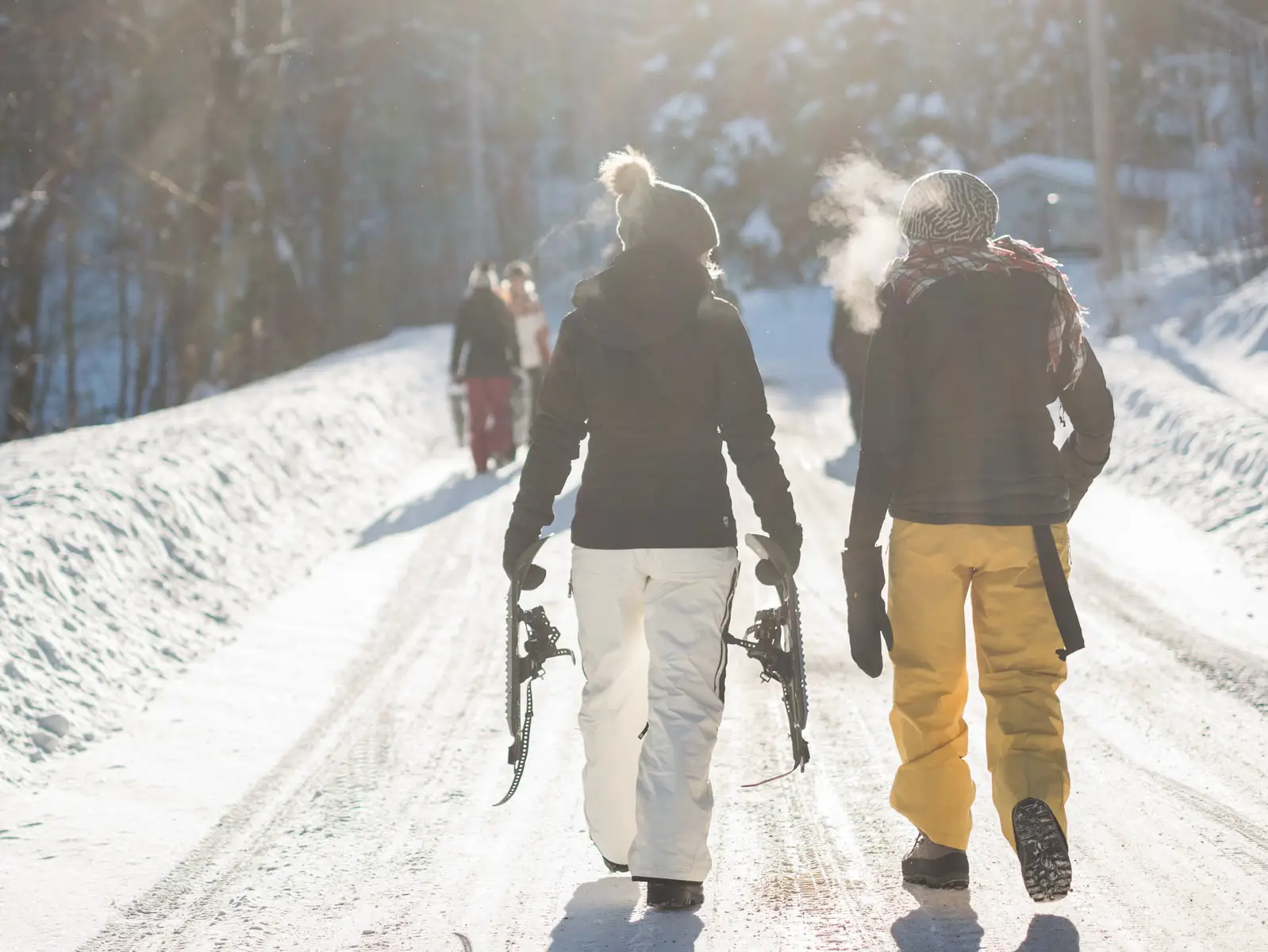 student holding snow ski blades while walking on snowy mountain during daytime