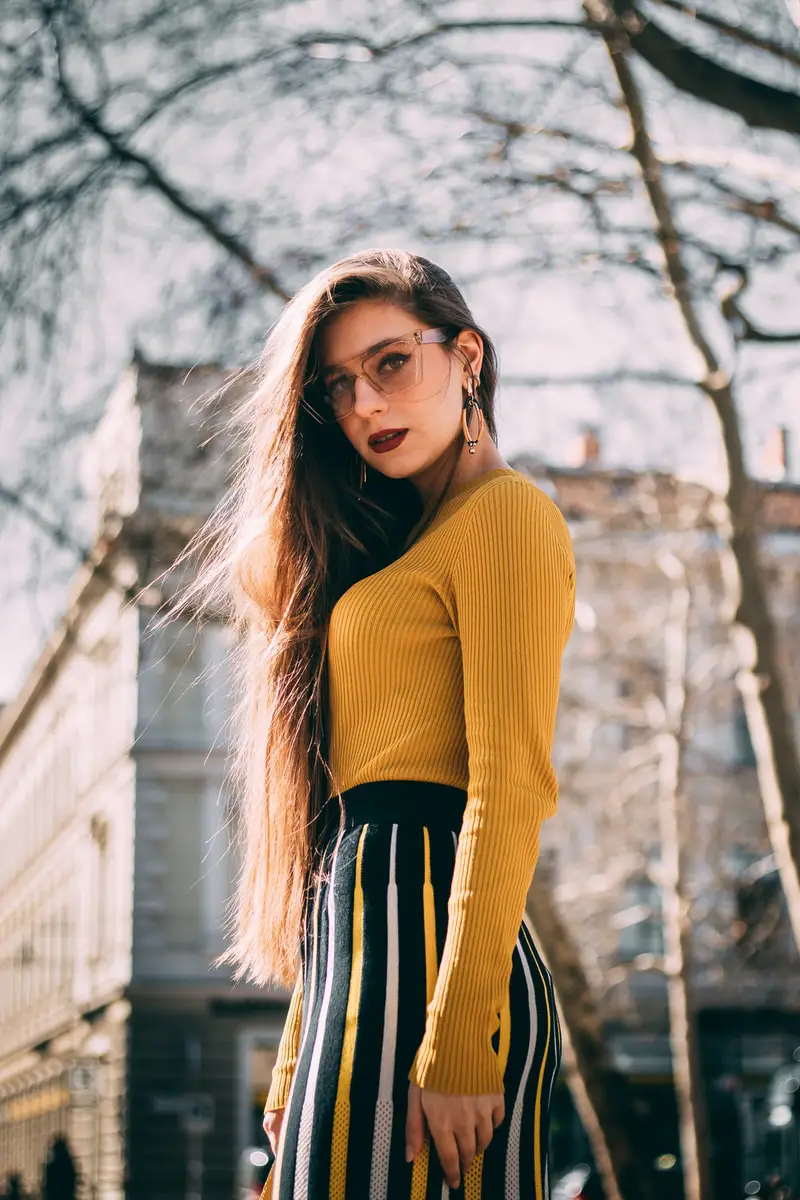 student in yellow long-sleeve shirt near concrete building during daytime