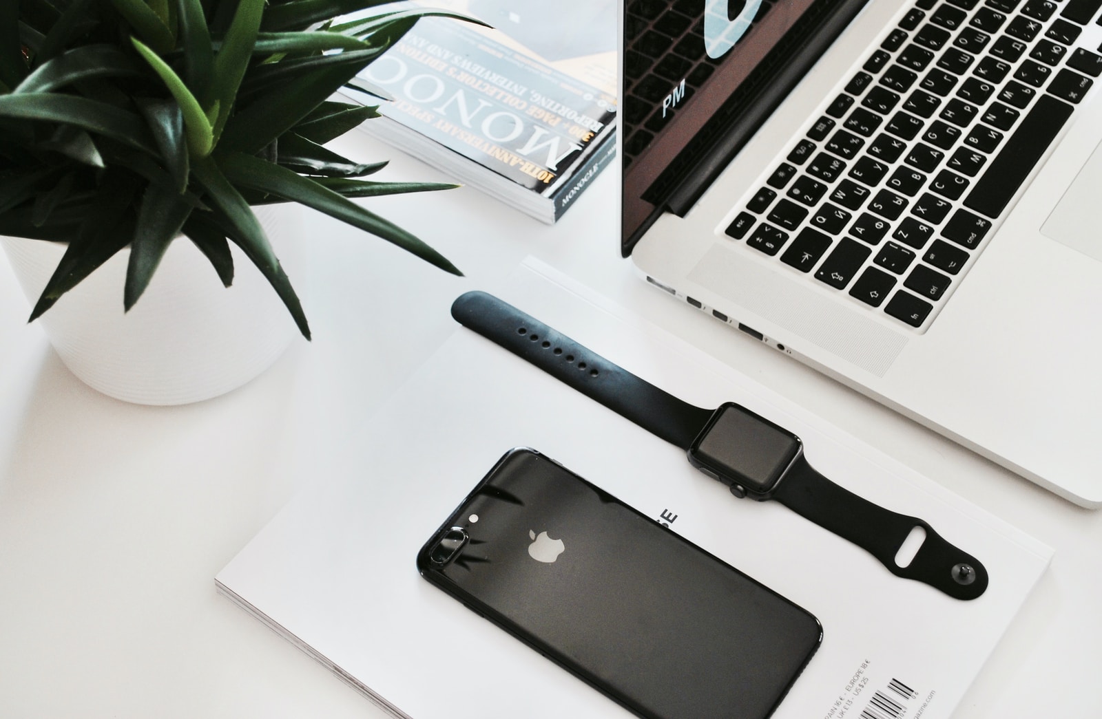 space black stainless steel Apple Watch on table beside the Apple MacBook Pro