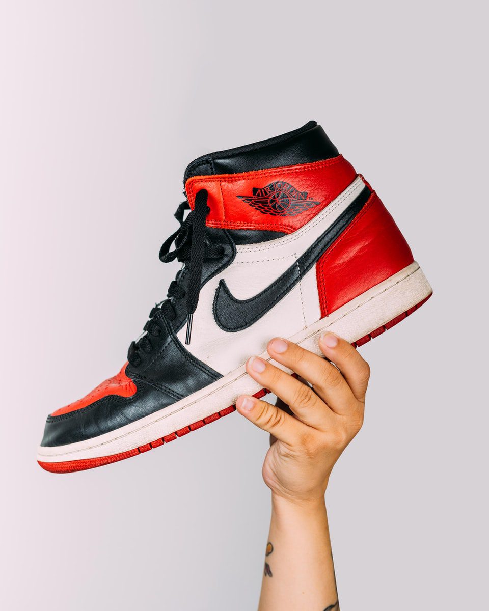 student holding red and white nike air jordan 1 shoe
