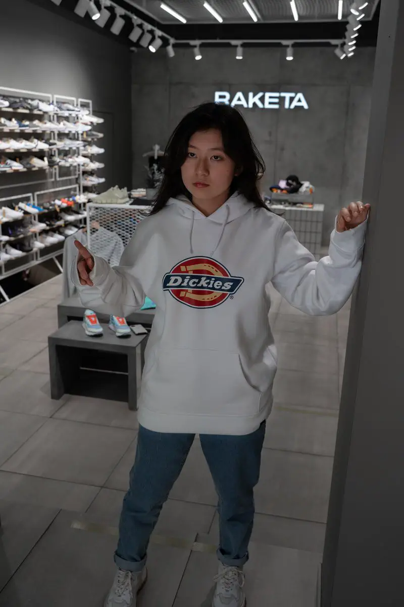 student in white dickies hoodie standing near counter