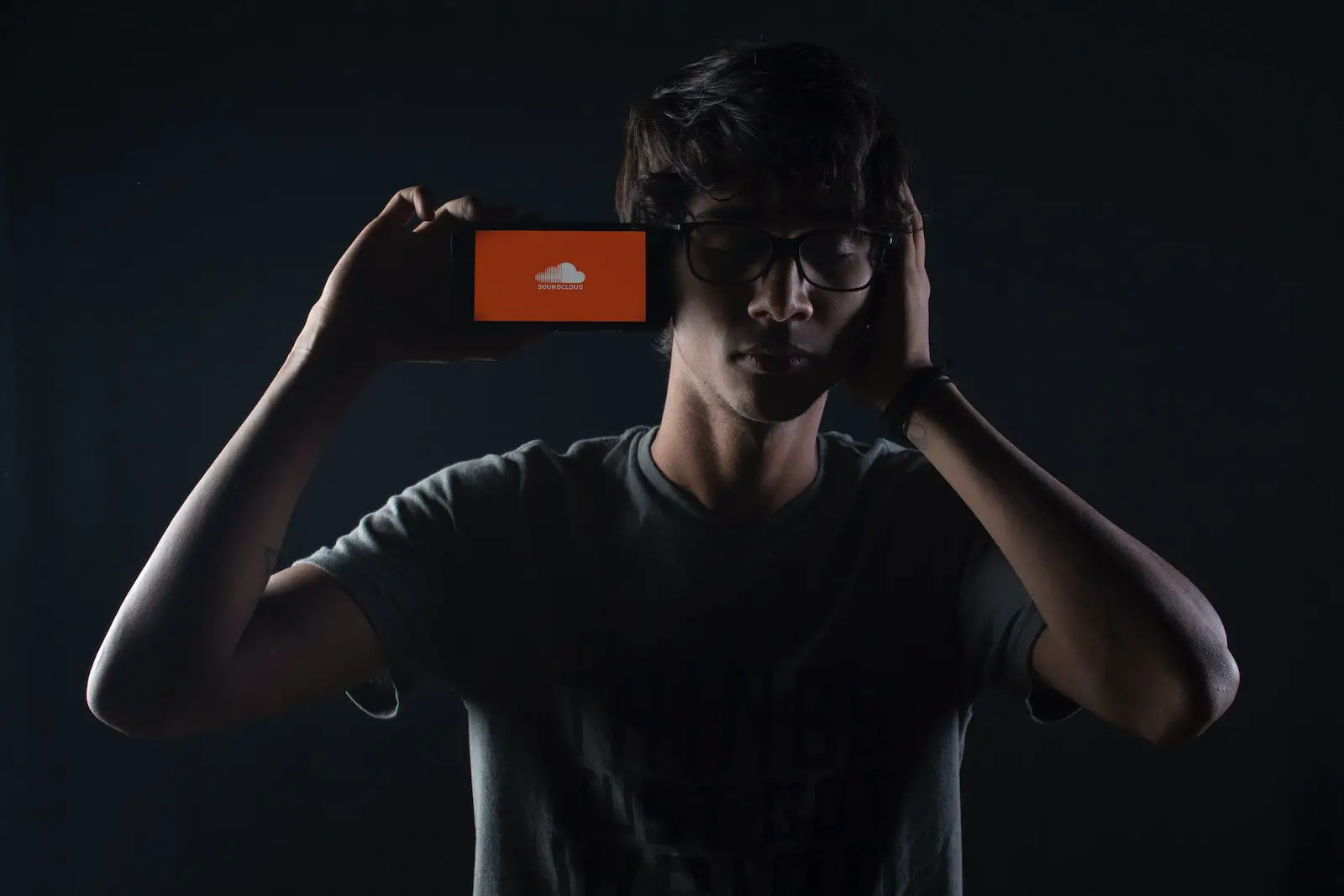 student listening to Soundcloud music on smartphone