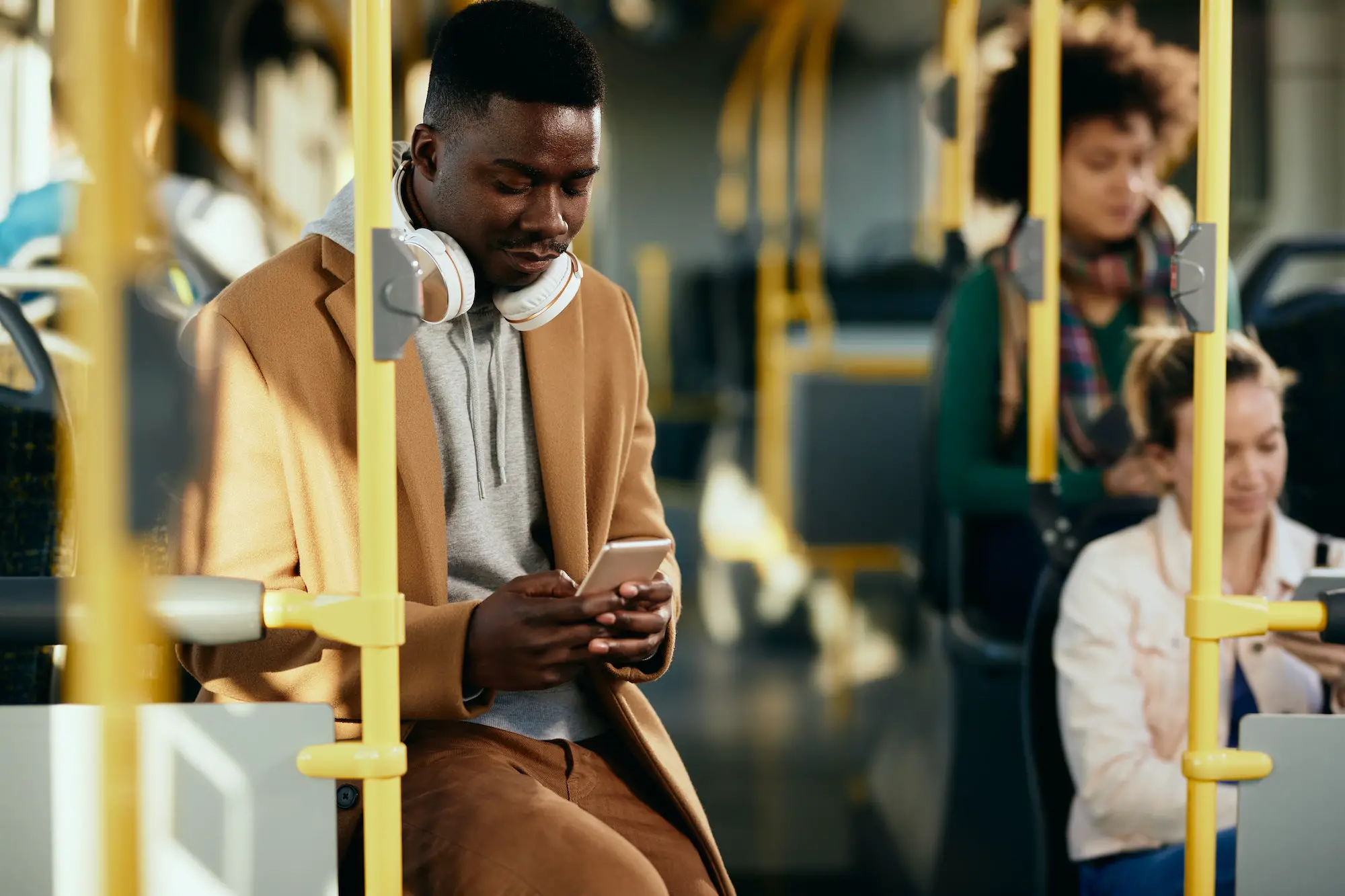African American man text messaging on cell phone while commuting by public transport.